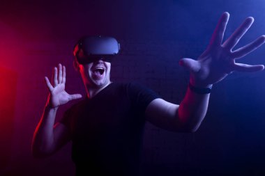 Korkak bir adam sanal gerçeklik oyun odasında bir oyuncu, VR gözlüklü bir adam bağırıyor ve bir tetikçiyi oynuyor.