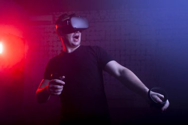 Korkak bir adam sanal gerçeklik oyun odasında bir oyuncu, VR gözlüklü bir adam bağırıyor ve bir tetikçiyi oynuyor.