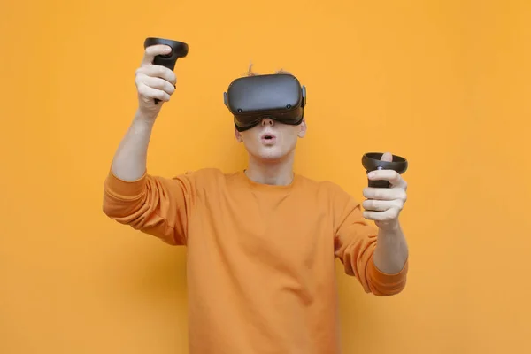 Fickó Vr szemüveg narancssárga háttér, a játékos tartja joysticks és játszik egy virtuális shooter — Stock Fotó