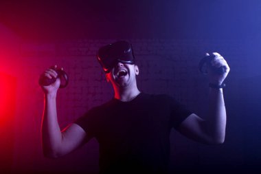 Korkak bir adam sanal gerçeklik oyun odasında bir oyuncu, VR gözlüklü bir adam bağırıyor ve bir tetikçiyi oynuyor.