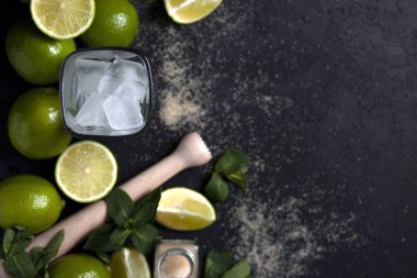 Ev yapımı kokteyl hazırlama süreci, siyah arka planda mojito malzemeleriyle dolu, ferahlatıcı bir yaz kokteyli.