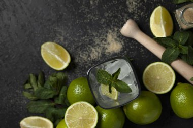Ev yapımı kokteyl hazırlama süreci, siyah arka planda mojito malzemeleriyle dolu, ferahlatıcı bir yaz kokteyli.