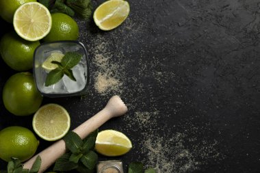 Ev yapımı kokteyl hazırlama süreci, siyah arka planda mojito malzemeleriyle dolu, ferahlatıcı bir yaz kokteyli.