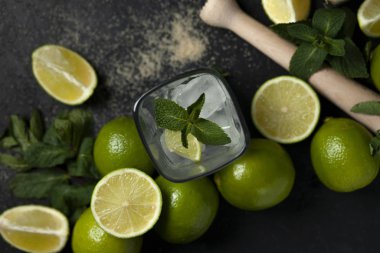 Ev yapımı kokteyl hazırlama süreci, siyah arka planda mojito malzemeleriyle dolu, ferahlatıcı bir yaz kokteyli.