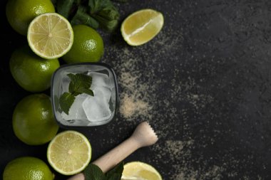 Ev yapımı kokteyl hazırlama süreci, siyah arka planda mojito malzemeleriyle dolu, ferahlatıcı bir yaz kokteyli.