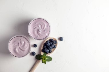 iki taze yaban mersinli yoğurt beyaz dokuma masasında, üst manzara