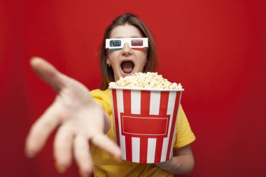 shocked girl in 3D glasses watching a movie and screaming on a red background