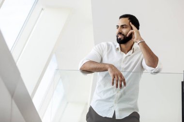 Portrait of a successful handsome man in a white shirt in the morning in a white building, businessman looks out the window