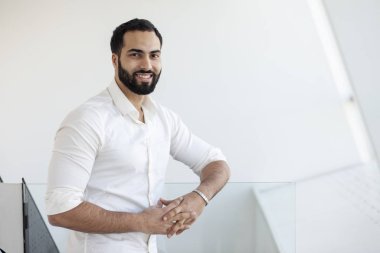 Portrait of a successful handsome man in a white shirt in the morning in a white building, businessman looks out the window