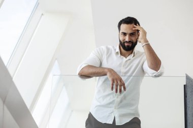 Portrait of a successful handsome man in a white shirt in the morning in a white building, businessman looks out the window