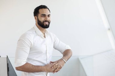 Portrait of a successful handsome man in a white shirt in the morning in a white building, businessman looks out the window, copy space