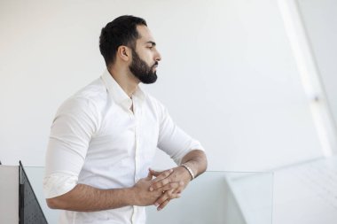 Portrait of a successful handsome man in a white shirt in the morning in a white building, businessman looks out the window, copy space