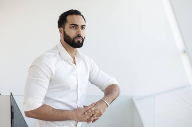 Portrait of a successful handsome man in a white shirt in the morning in a white building, businessman looks out the window, copy space