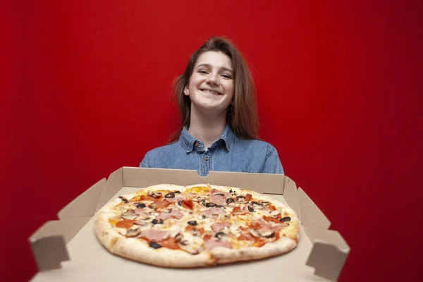 Молодая Счастливая Девушка Держит Большую Пиццу Коробке Цветном Красном Фоне — стоковое фото
