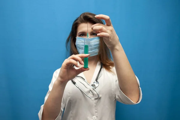 Ung Flicka Sjuksköterska Mask Håller Spruta Blå Bakgrund Läkaren Ger — Stockfoto