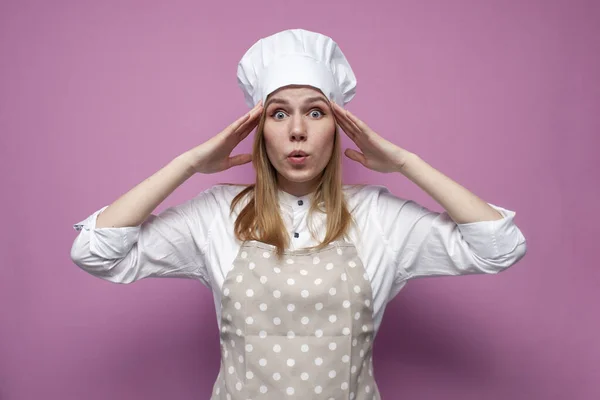 Menina Surpresa Cozinheiro Avental Segurar Mãos Atrás Cabeça Fundo Rosa — Fotografia de Stock