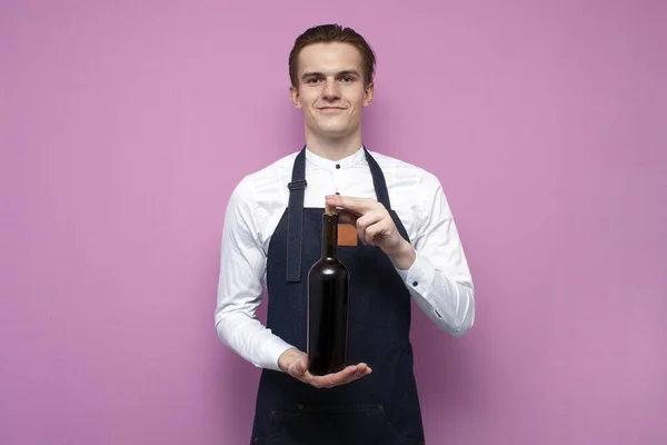 Joven Camarero Profesional Uniforme Sostiene Una Botella Vino Tinto Sonríe — Foto de Stock