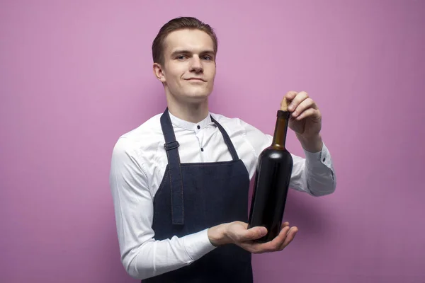 Joven Camarero Profesional Uniforme Sostiene Una Botella Vino Tinto Sonríe — Foto de Stock
