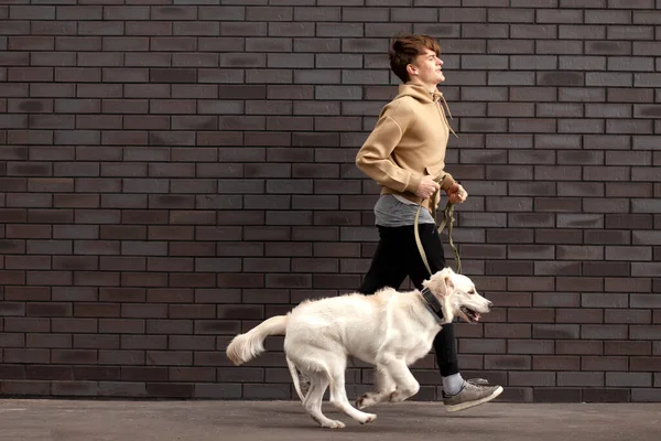 Jonge Man Rent Met Een Hond Straat Tegen Achtergrond Van — Stockfoto