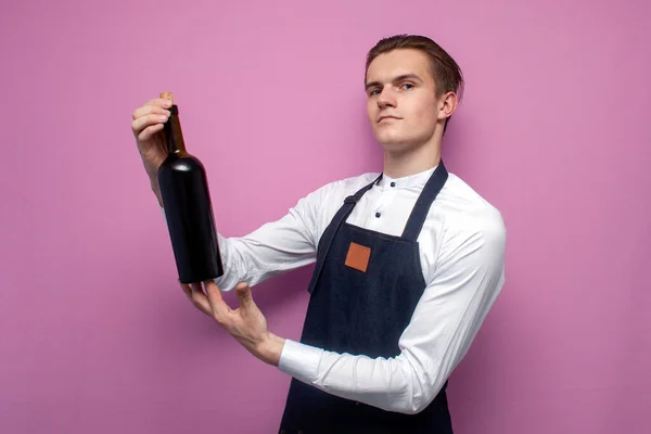 Joven Camarero Profesional Uniforme Sostiene Una Botella Vino Tinto Sonríe — Foto de Stock