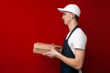 Kırmızı arka plandaki genç pizza teslimatçısı kutular dolusu yiyecek verir, kurye siparişi verir.