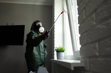 Dairede koronavirüs dezenfeksiyonu. Koruyucu giysili insanlar odayı virüslerden ve hastalıklardan, enfeksiyon temizleme servisinden profesyonel olarak temizliyorlar.
