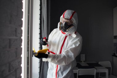 Dairede koronavirüs dezenfeksiyonu. Koruyucu giysili insanlar odayı virüslerden ve hastalıklardan, enfeksiyon temizleme servisinden profesyonel olarak temizliyorlar.
