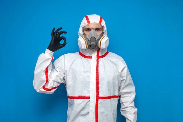 Profesionální Dezinfekční Muž Ochranném Obleku Ukazuje Pořádku Znamení Modrém Izolovaném — Stock fotografie