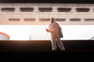 Şehrin virüslerden ve enfeksiyonlardan dezenfekte edilmesi. Koruyucu giysili bir hijyen işçisi ve solunum cihazı şehri kimyasal bir maddeyle temizliyor.