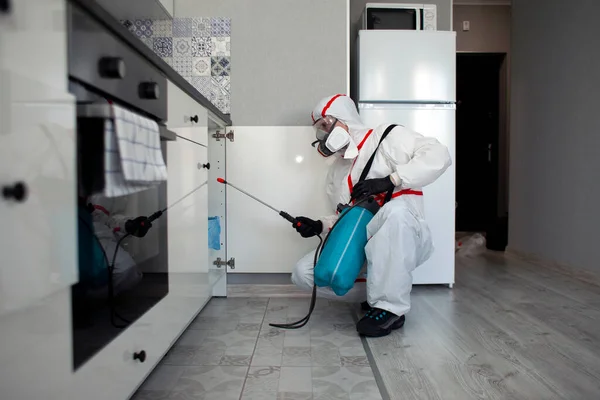 disinfection of the room from coronavirus. a man in a protective suit cleans the apartment of infections with a chemical agent, sanitary cleaning service