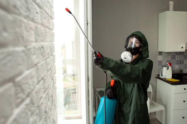 disinfection of the room from coronavirus. a man in a protective suit cleans the apartment of infections with a chemical agent, sanitary cleaning service