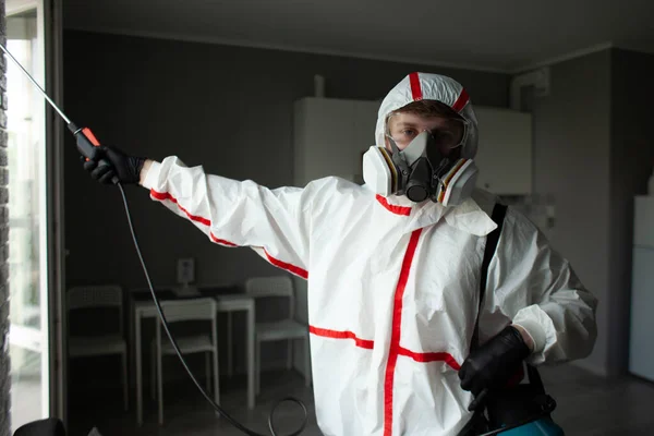 Disinfection worker in protective equipment against the background of the apartment, disinfection of the premises from viruses and infections, sanitation service