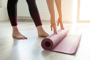 Yoga zamanı. Yalınayak kız evde yoga minderini açıyor, sporcu kadın yoga yapmaya hazır, yakın plan.