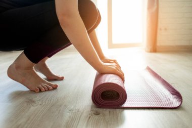 Yoga zamanı. Yalınayak kız evde yoga minderini açıyor, sporcu kadın yoga yapmaya hazır, yakın plan.