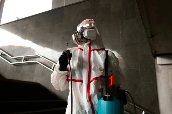portrait of a disinfection service worker in a protective suit and a respirator against a city background, a sanitary worker, close-up