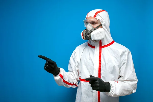 コロナウイルスのパンデミック 防護服を着た消毒作業員と呼吸器は青い隔離された背景のテキスト ウイルス学者のための場所に指を示しています — ストック写真