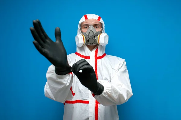 コロナウイルスに対する耐性 防護服とマスク服の消毒作業員手袋青の隔離された背景のウイルス学者 — ストック写真