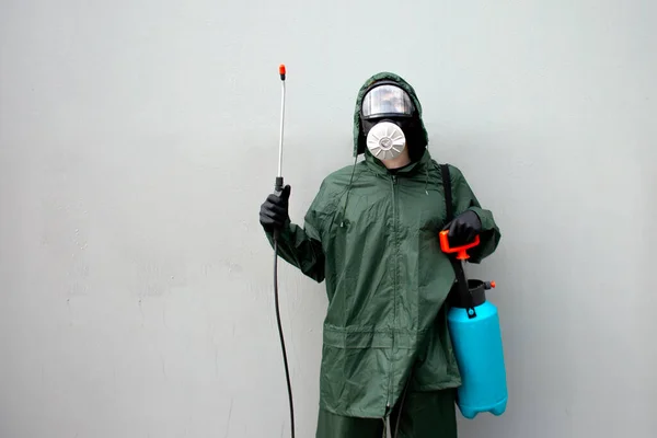 disinfection of the city from coronavirus, a man in a protective suit and a respirator against the background of the city wall, a sanitary worker, copy space