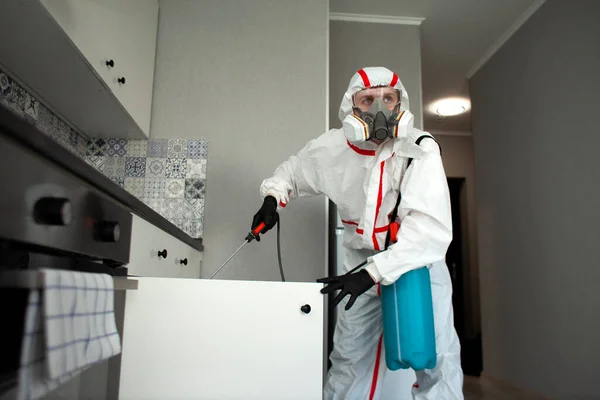 コロナウイルスからの部屋の消毒 防護服を着た男が化学物質で感染症のアパートを清掃する衛生清掃サービス — ストック写真