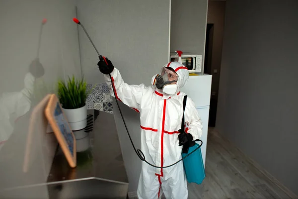 防護服を着た男と呼吸器はアパートを化学物質で消毒し衛生作業員はコロナウイルスから部屋を掃除します — ストック写真