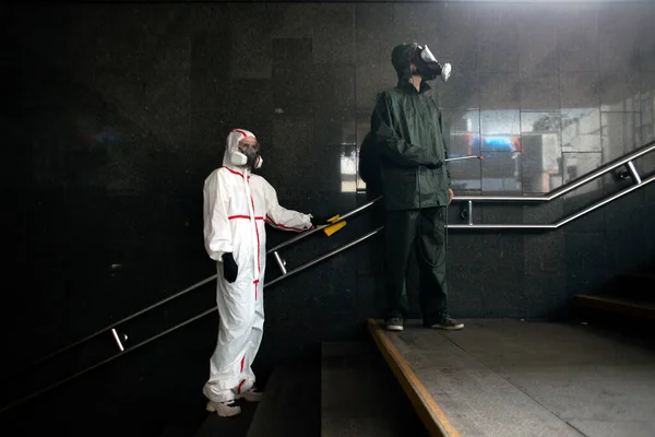 防護服を着た2人ハズマットはウイルスや感染症から手すりを消毒公共の場所の消毒 — ストック写真