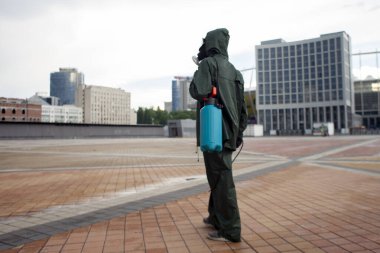 Şehrin virüslerden ve enfeksiyonlardan dezenfekte edilmesi. Koruyucu giysili bir hijyen işçisi ve solunum cihazı şehri kimyasal bir maddeyle temizliyor.