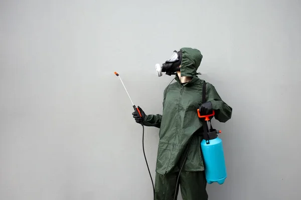 disinfection of the city from coronavirus, a man in a protective suit and a respirator against the background of the city wall, a sanitary worker, copy space
