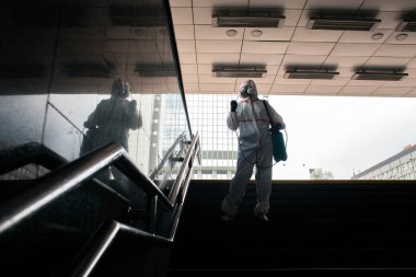 Şehrin virüslerden ve enfeksiyonlardan dezenfekte edilmesi. Koruyucu giysili bir hijyen işçisi ve solunum cihazı şehri kimyasal bir maddeyle temizliyor.