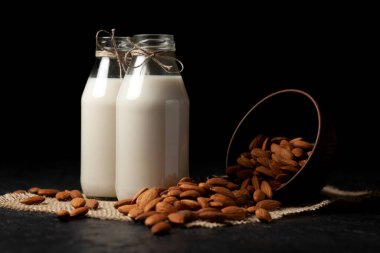Siyah bir masada fındıklı badem sütü, şekersiz ve laktozsuz çeşitli süt ürünleri, vejetaryen içeceği.