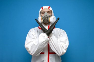 Kimyasal koruyucu giysili bir adam mavi izole bir arka planda dur işareti gösterir, epidemiyolog, biyolog, virolog, bilim adamı.