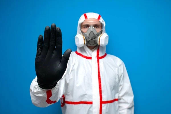 化学保護訴訟の医師のウイルス学者は 青い隔離された背景に手を停止標識を示しています 疫学者は家を出ることを禁止します — ストック写真
