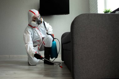 Haşere kontrolü. Böceklere ve kemirgenlere karşı kimyasal yollarla dezenfekte edilmiş bir bina. Evin arka planında spreyi olan bir hijyenik işçi.