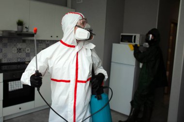 Haşere kontrolü. Böceklere ve kemirgenlere karşı kimyasal yollarla dezenfekte edilmiş bir bina. Evin arka planında spreyi olan bir hijyenik işçi.