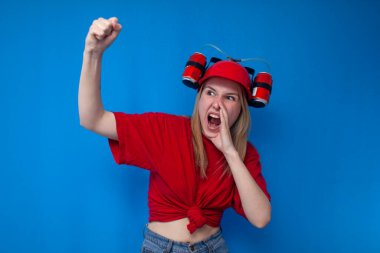 Çılgın komik kız kırmızı üniformalı ve bira şapkalı bir hayran takımını destekliyor ve bağırıyor, amigo kız zaferden memnun.